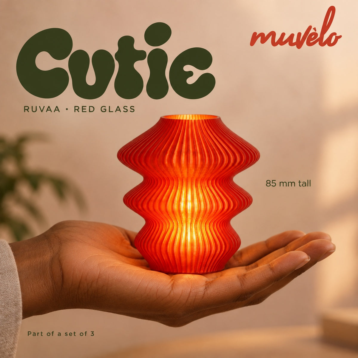 Illuminated Red Glass Ruvaa Cutie resting on an adult palm, with soft retro Cutie lettering and the official Muvèlo wordmark.
