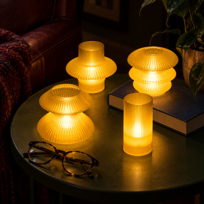 Yellow Glass Cuties glowing beside a navy book and reading glasses in a dark reading nook.
