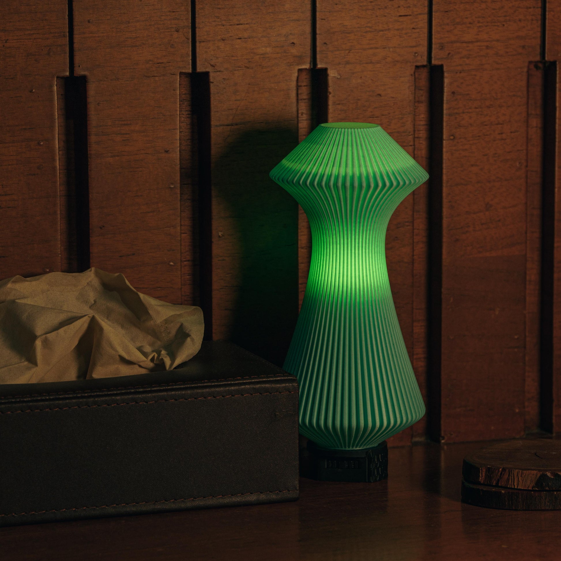 Green textured lamp on a wooden surface with a dark background