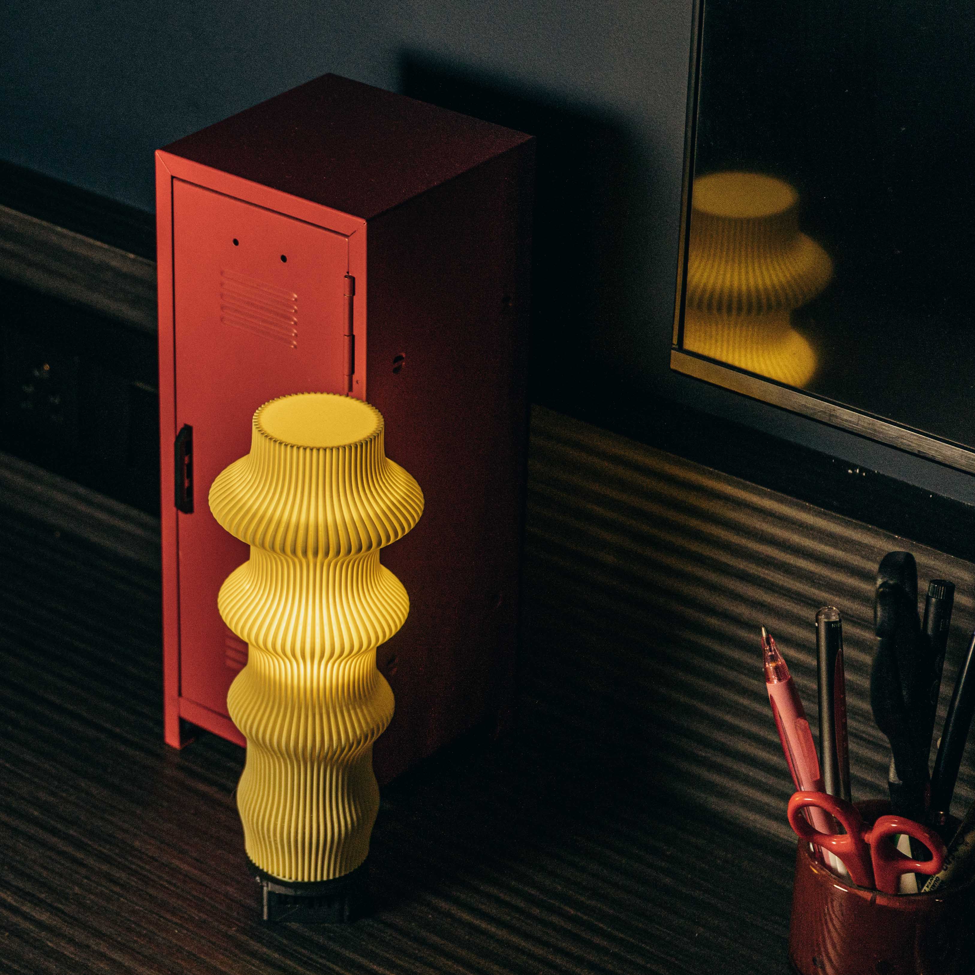 Yellow lamp on a desk with a laptop in the background
