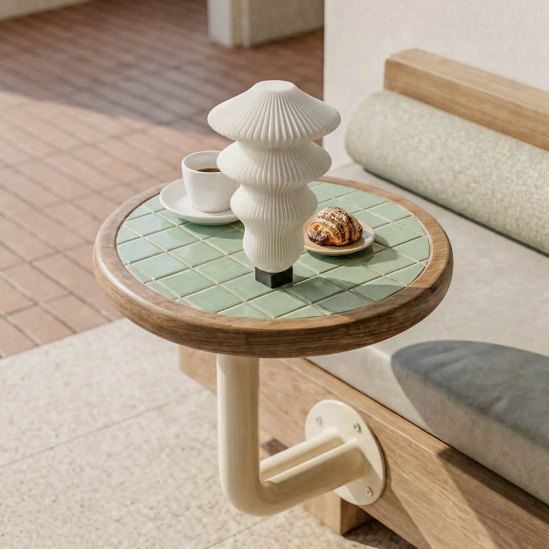 Small round table with green tiled surface and wooden edge, featuring a white ceramic vase and small items on a wooden floor.