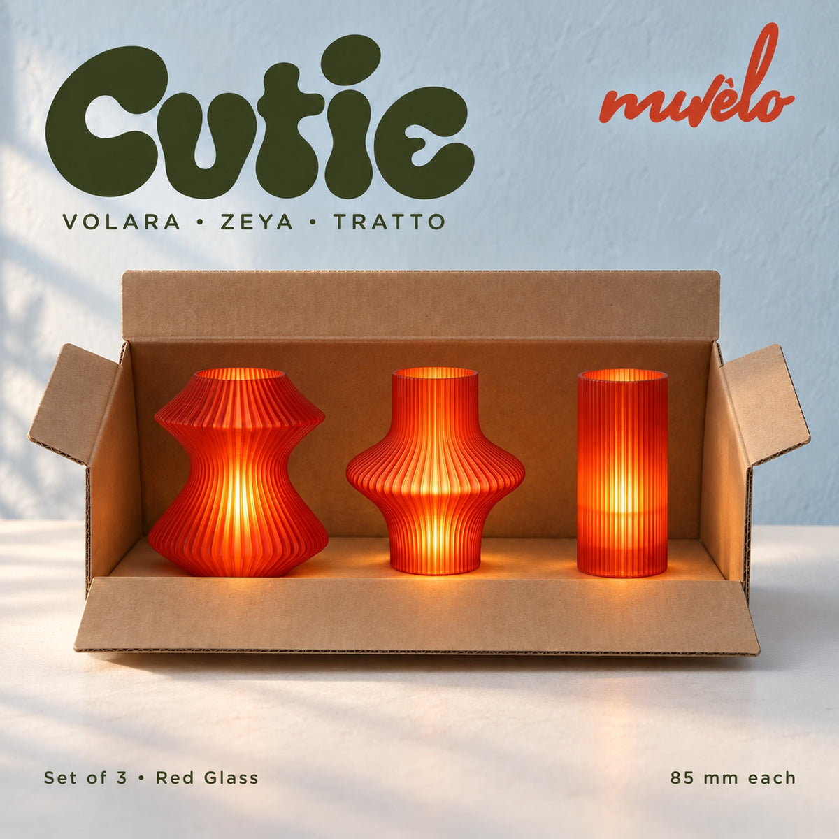 Three illuminated Red Glass Cutie lamps — Volara, Zeya, Tratto — displayed together in an open plain cardboard box.