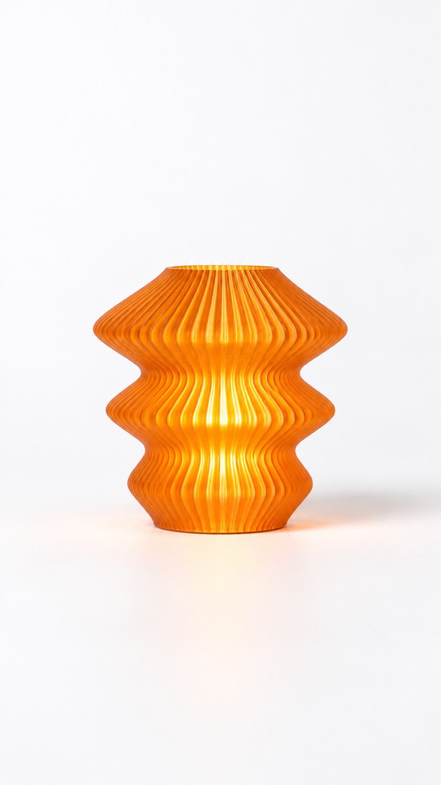 Orange Glass Ruvaa Cutie lamp glowing against a light background, showing its three wavy tiers.