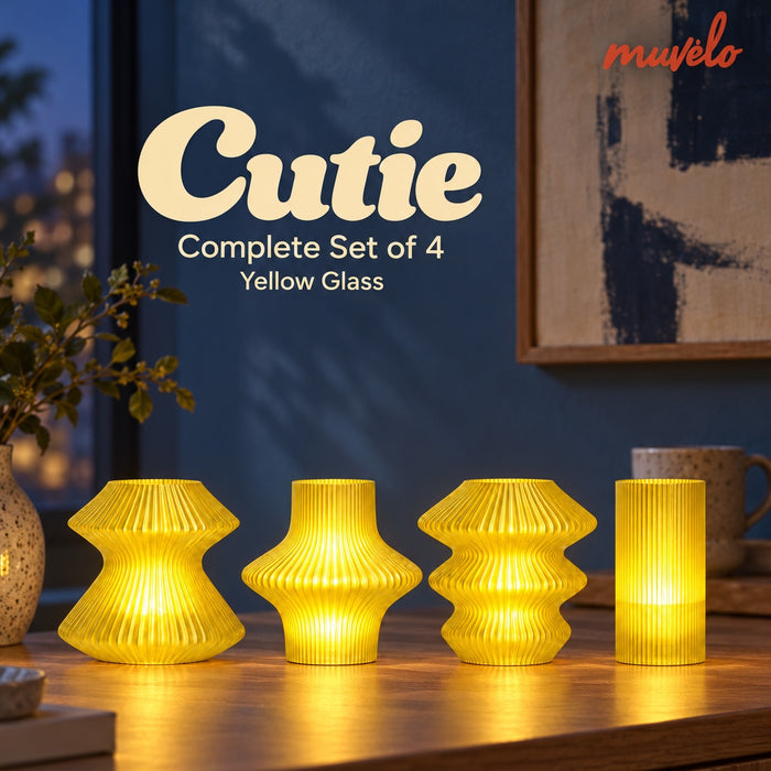 Four Yellow Glass Cutie lamps glowing on a wooden console against a blue wall.