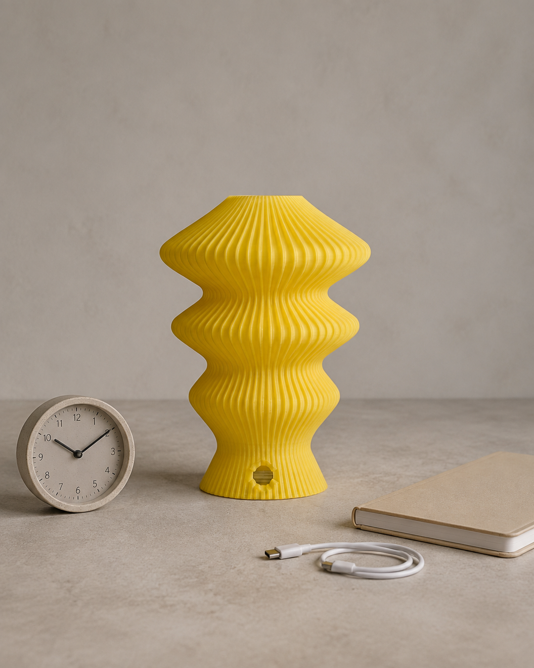 Yellow Muvèlo Ruvaa Mono beside a clock and USB-C cable for a battery guide
