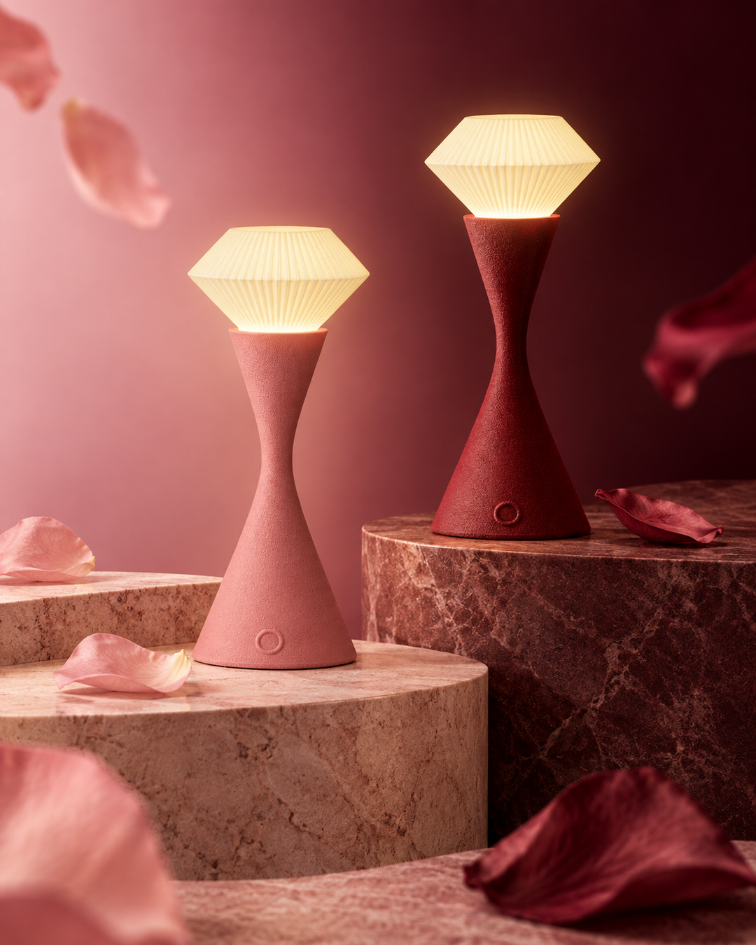Vela Blush Pink and Vela Maroon touch lamps compared on separate stone pedestals