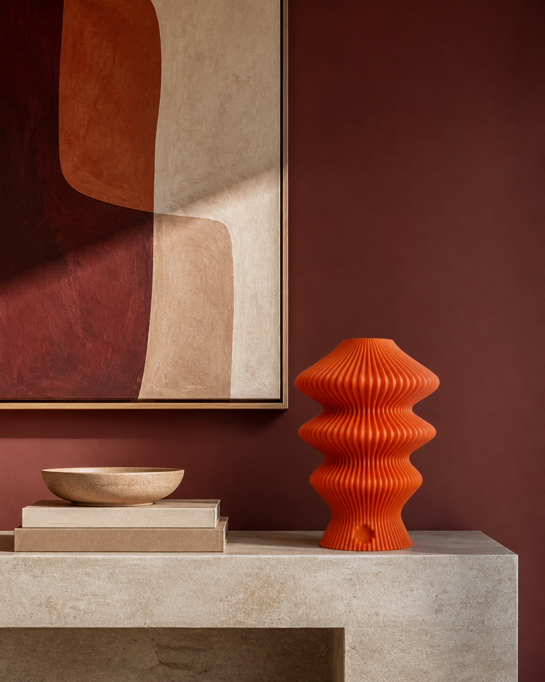 Orange Muvèlo Ruvaa Mono styled on a pale stone console below abstract art