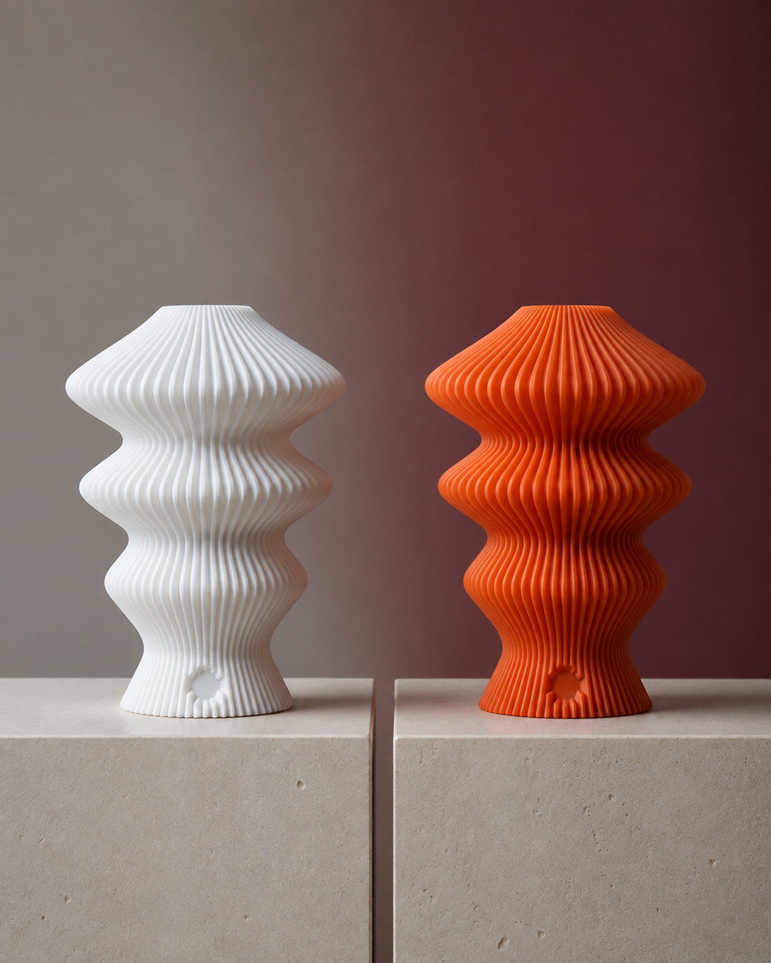 White and orange Muvèlo Ruvaa Mono lamps compared on equal stone plinths