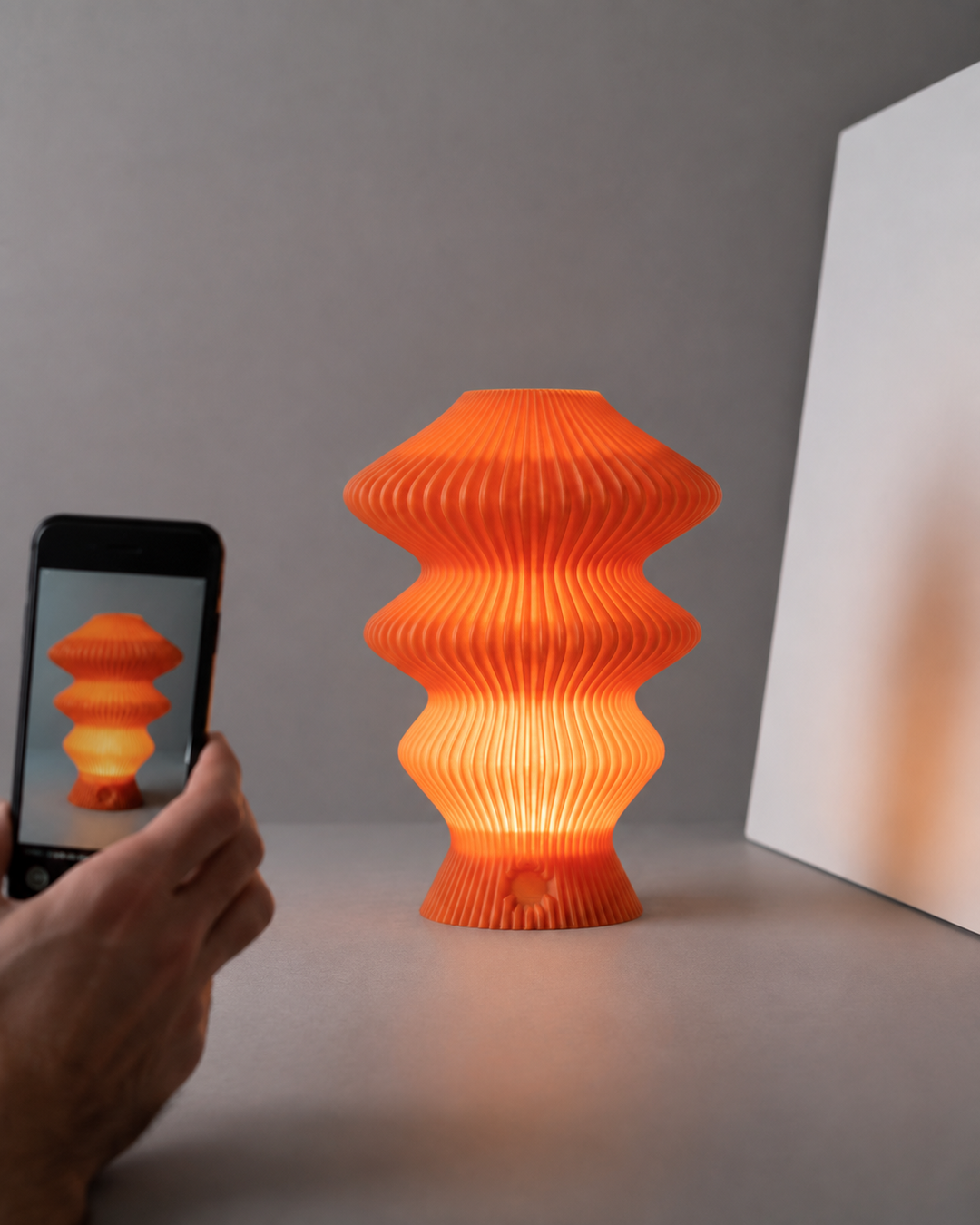 Orange Muvèlo Ruvaa Mono being photographed with a smartphone and reflector