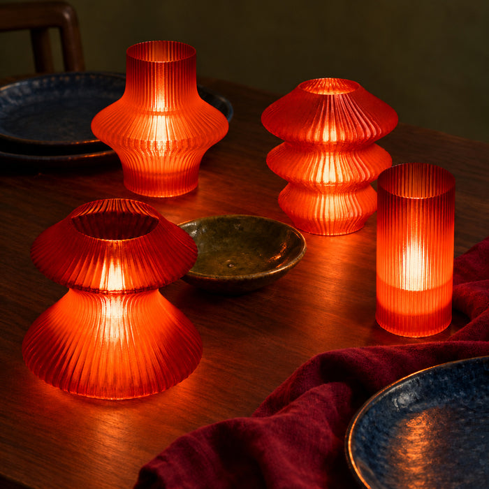 Four illuminated Red Glass Cuties—Volara, Ruvaa, Zeya and Tratto—placed at different depths on a dark walnut supper table.