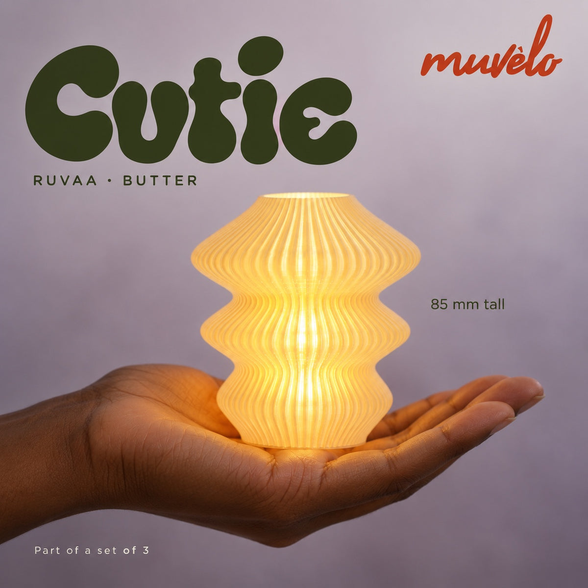 Illuminated Butter Ruvaa Cutie resting on an adult palm, with soft retro Cutie lettering and the official Muvèlo wordmark.