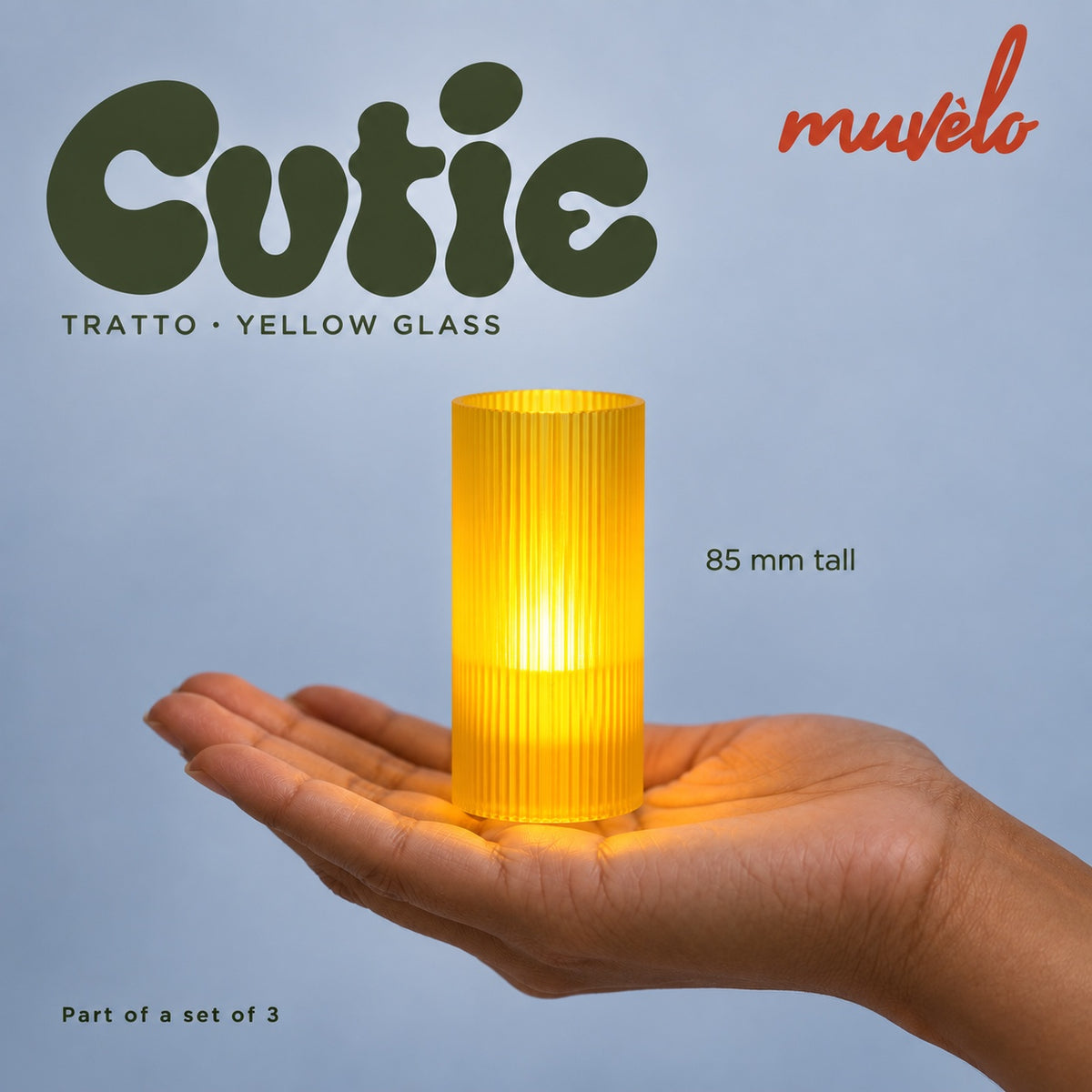 Illuminated Yellow Glass Tratto Cutie resting on an adult palm, with soft retro Cutie lettering and the official Muvèlo wordmark.