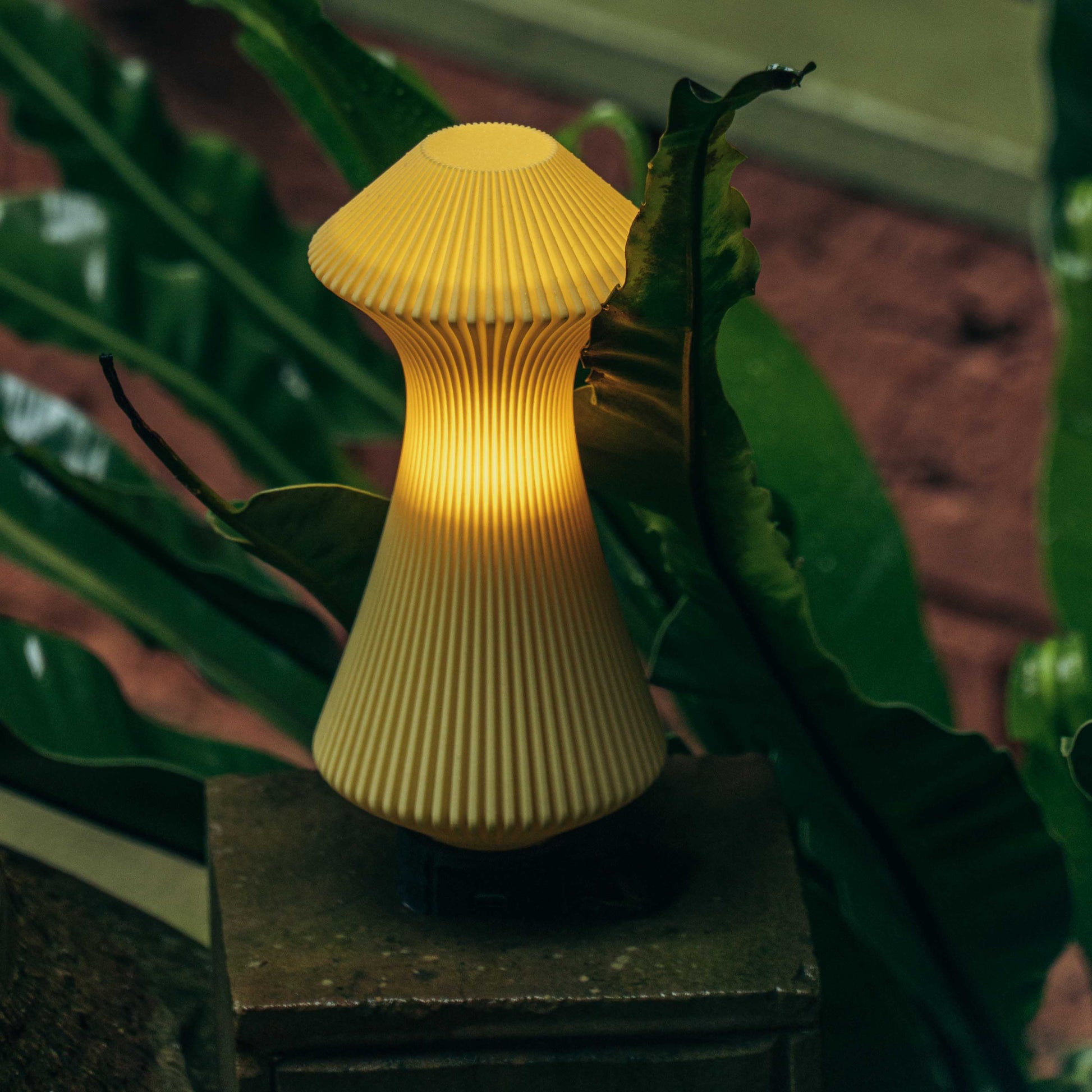 Yellow mushroom-shaped lamp on a stand with green leaves in the background