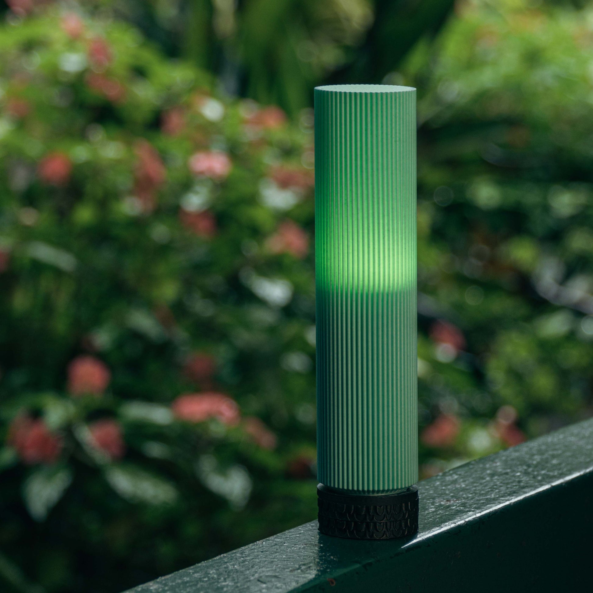 Green cylindrical object on a ledge with a blurred natural background