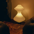 Decorative lamp with ribbed texture on a wooden surface, casting a warm glow.