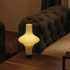 Decorative table lamp on a wooden surface with a brown upholstered chair in the background