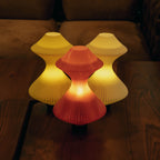 Three colorful table lamps on a wooden surface with a dark background