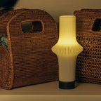 Decorative lamp with ribbed design in front of wicker furniture