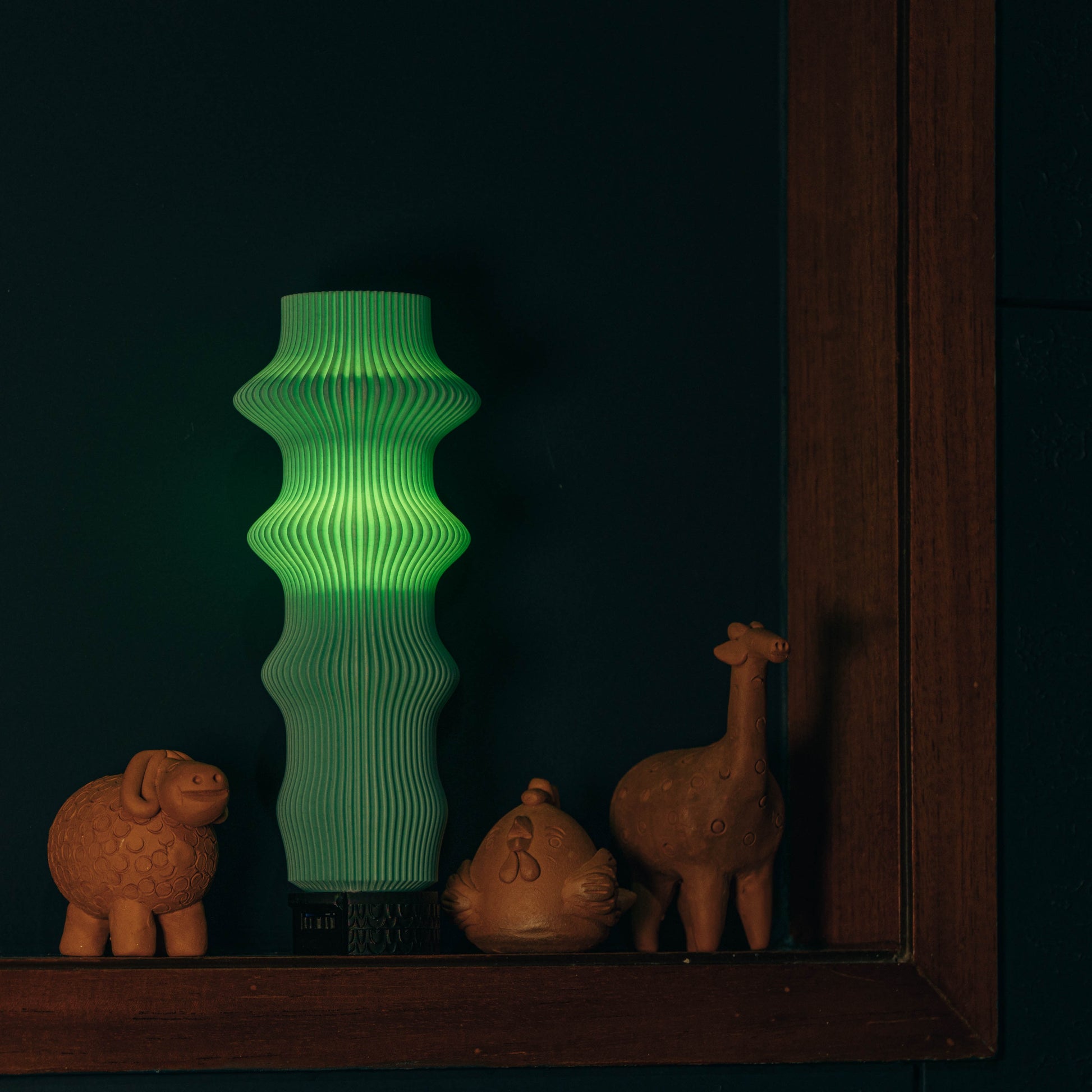Green textured lamp with animal figurines on a dark background