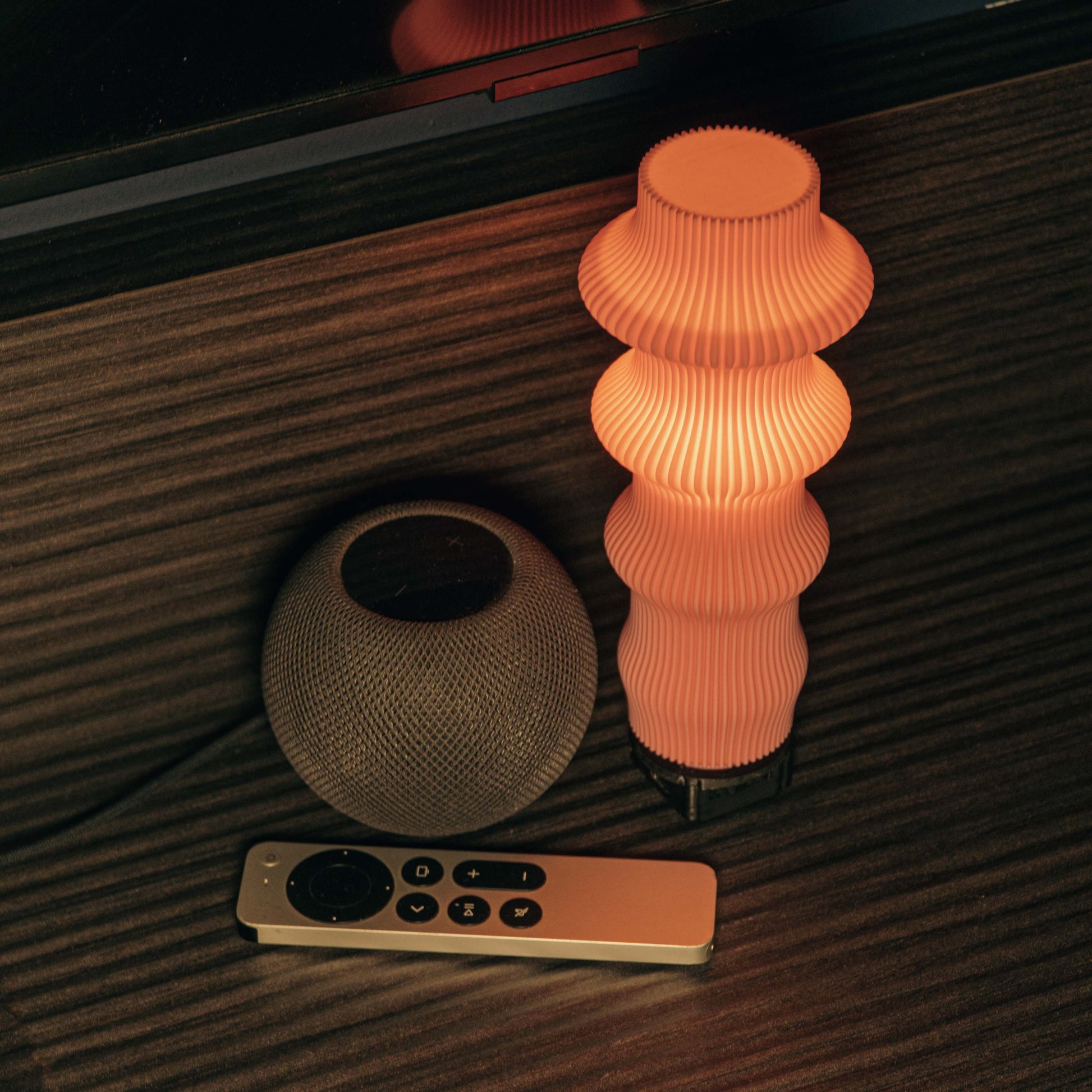 Decorative lamp with a smart speaker and remote control on a wooden surface