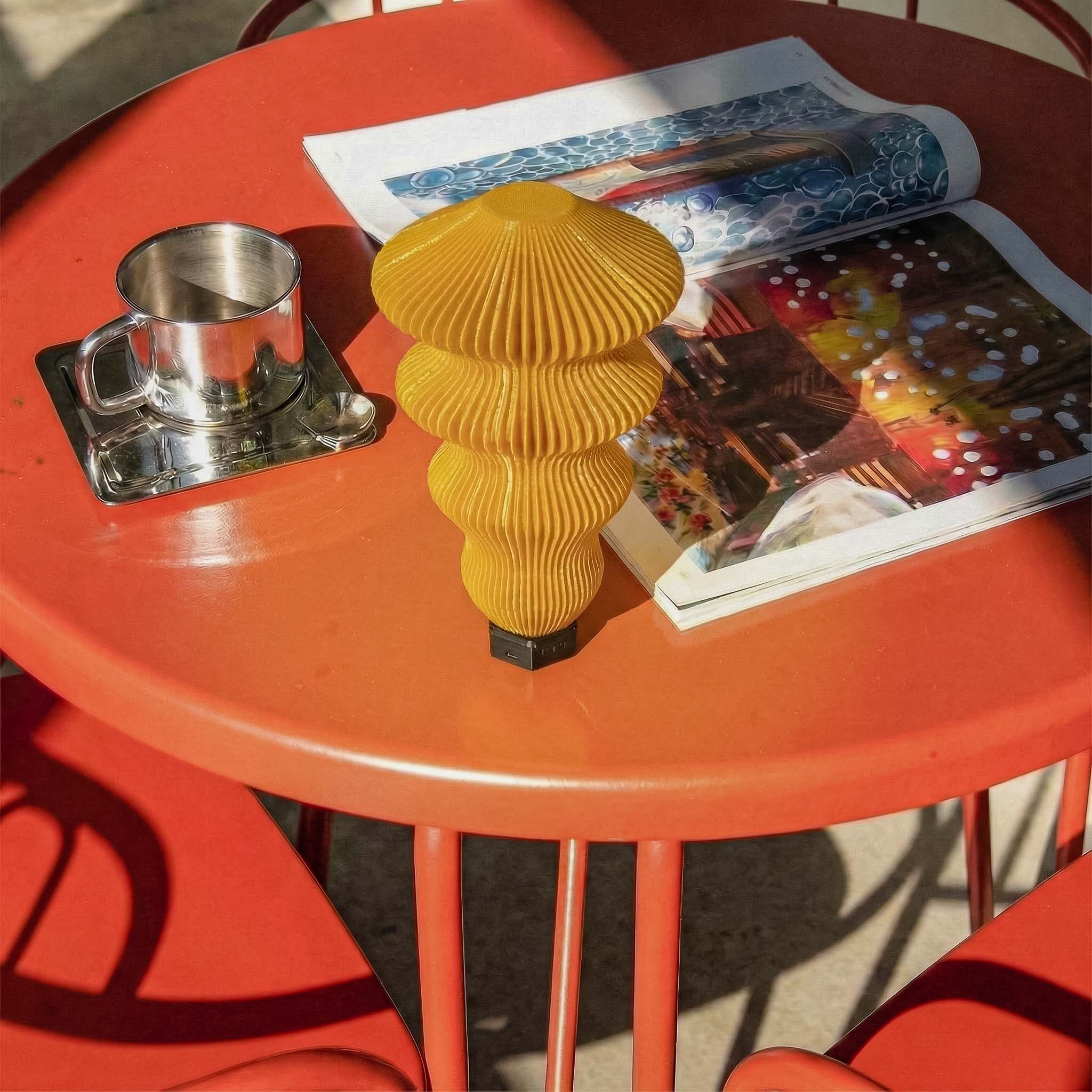 Yellow textured PORTABLE MODULAR TABLE LAMP on a red table with a magazine