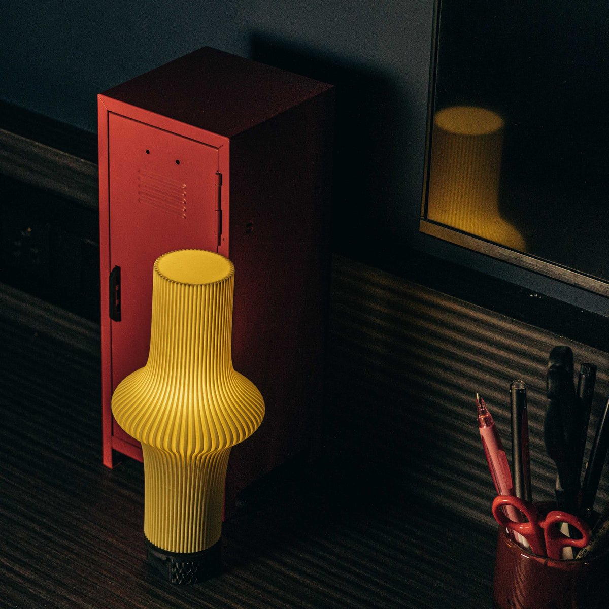 Yellow ribbed stool next to a red locker in a dimly lit room.