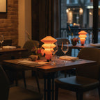 Dining table set with wine glasses, a lamp, and decor in a cozy restaurant setting.