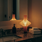 Decorative lamp on a bathroom counter with towels and soap.