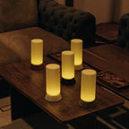 Five cylindrical string lights on a wooden table in a dimly lit room.