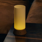 Yellow cylindrical lamp on a wooden surface with a brown fabric background