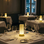 Dining tables set for a meal with candles and glasses in a dimly lit restaurant.