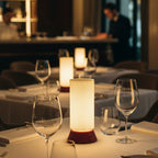 Dining table setup with wine glasses, candles, and a lamp in a restaurant setting.