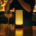 Bartender preparing a drink at a bar with a lit lamp on the counter.