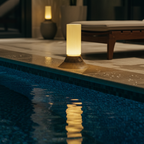 Poolside setting with a lit lantern and lounge chair in a dimly lit room.