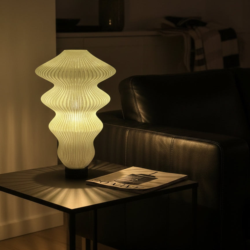 Decorative lamp on a table in a dimly lit room with a couch in the background
