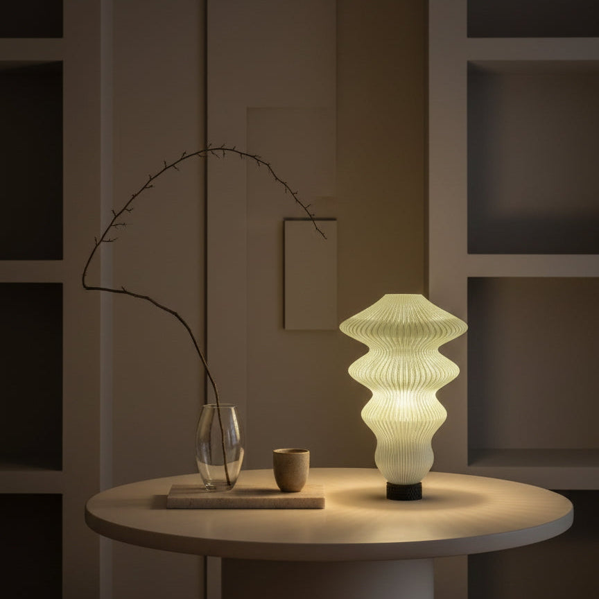 Modern table lamp on a round table with minimal decor in a dimly lit room.