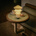 Small round table with a unique lamp and a cup on a dimly lit background