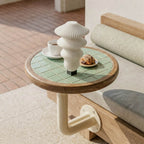 Small round table with green tiled surface and wooden edge, featuring a white ceramic vase and small items on a wooden floor.