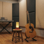 Acoustic guitar on a stand next to a stool with a lamp in a room with soundproofing panels.