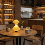 Wooden table with a lamp and cups in a cozy bar setting