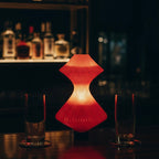 Red lamp on a bar counter with glasses and bottles in the background