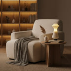 Beige armchair with a side table and lamp in a cozy living room setting.