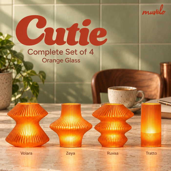 Four Orange Glass Cutie lamps glowing on a stone coffee counter beside a cup: Volara, Zeya, Ruvaa and Tratto.