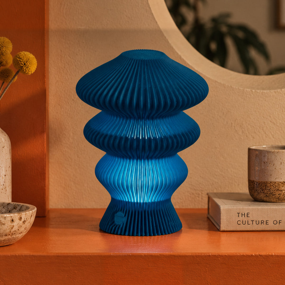 Muvèlo Ruvaa Mono Blue table lamp glowing on an orange console in a retro interior