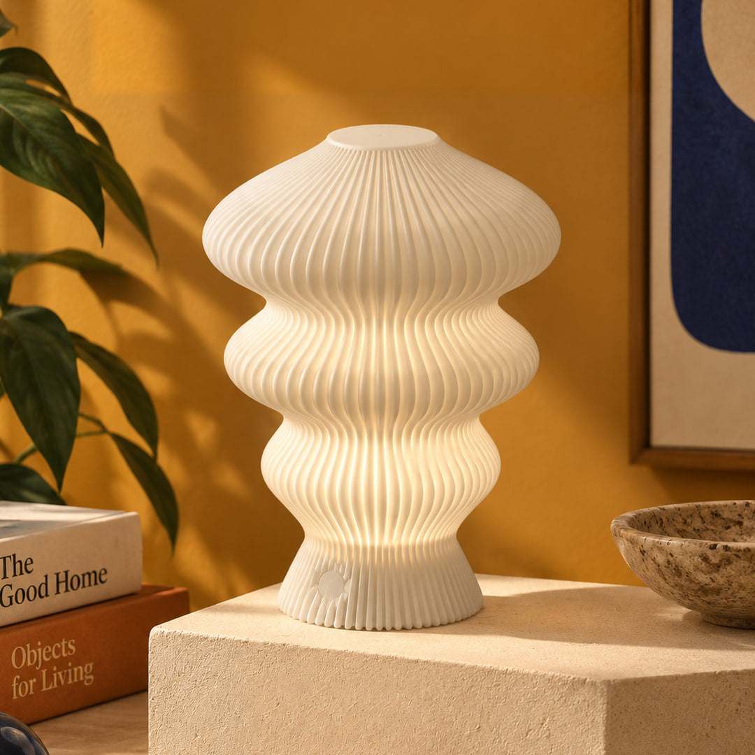 Muvèlo Ruvaa Mono White table lamp glowing on a stone display plinth in a retro interior