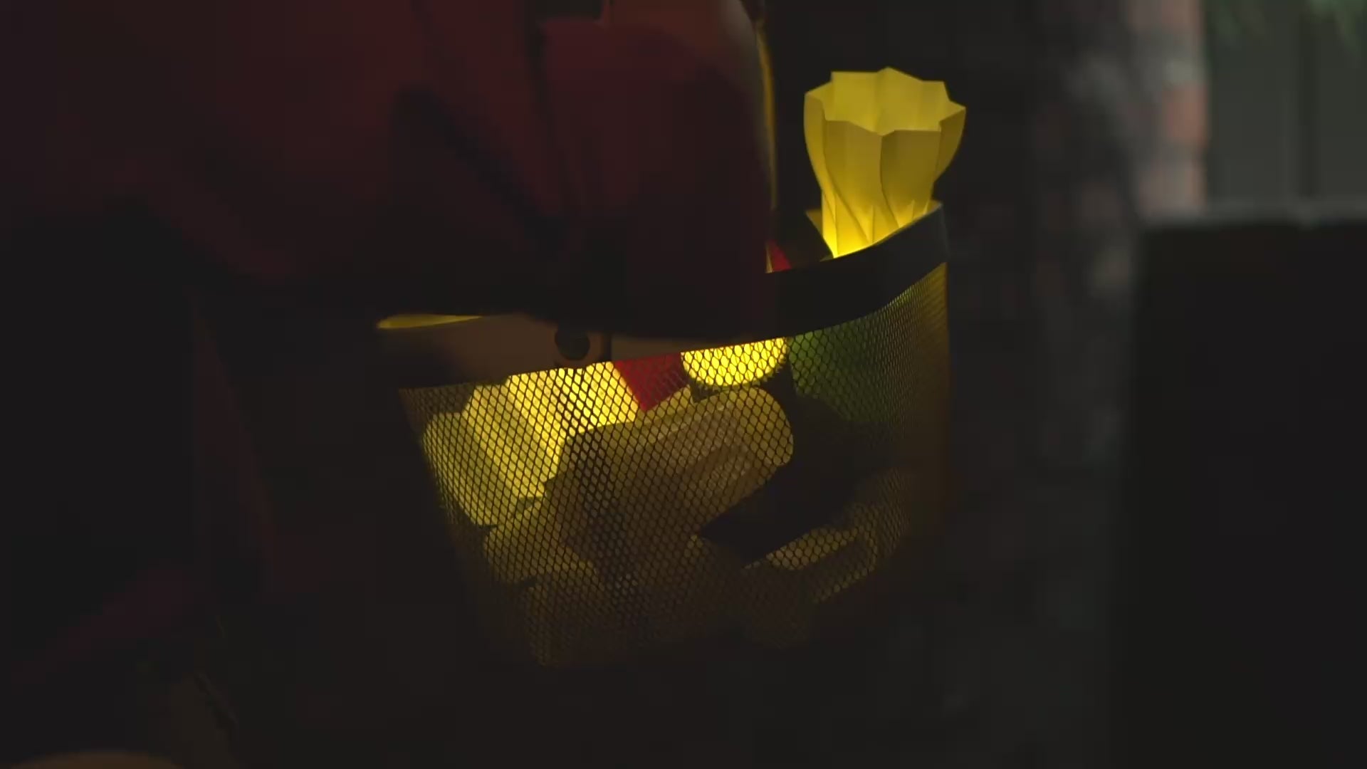 Muvelo Vaari Lamp in a basket, with a woman holding the basket in her hand. and waving it across