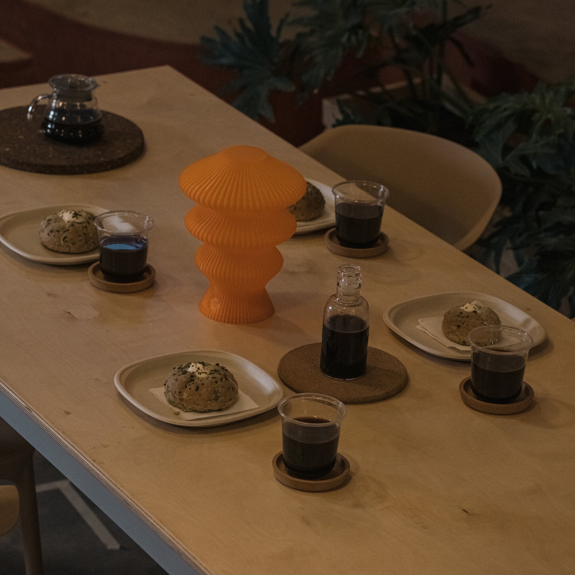 Orange Ruvaa Mono lamp switched off on a dining table in warm room light