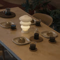 White Ruvaa Mono rechargeable ambient table lamp glowing on a dining table