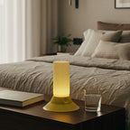 Yellow table lamp on a nightstand next to a bed in a bedroom setting