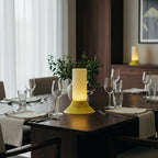 Dining table set with wine glasses and a yellow lamp in a well-lit room.